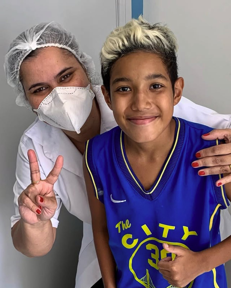 Enzo sorrindo e fazendo sinal de positivo ao lado da dentista