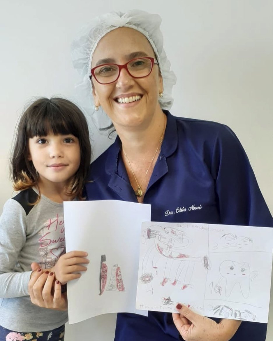 Manu ao lado da Dra. Cátia, segurando desenhos que fez