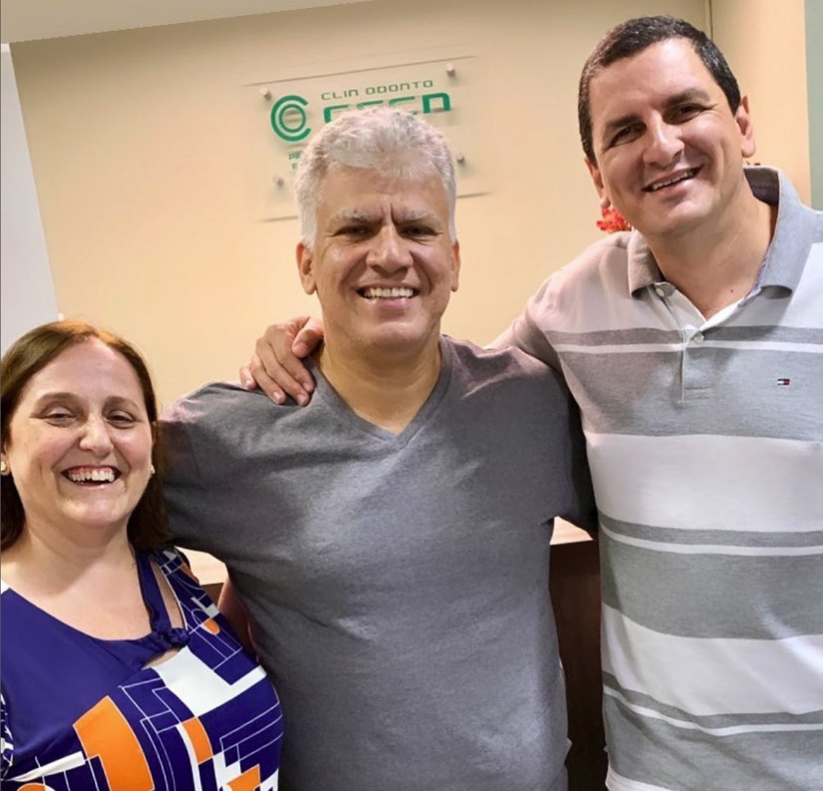 Rogério e Mirian com o Dr. Carlos na recepção, em frente à placa da clínica